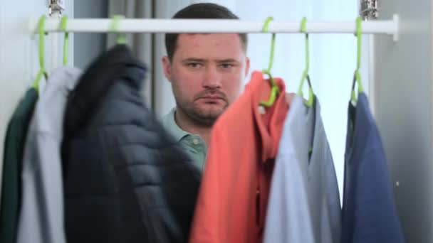 L'homme blanc d'Unshaven ouvre la garde-robe le matin et choisit les vêtements, passe à travers la garde-robe, confectionne la veste bleue de choix pour aller au travail. Robes Guy pour dattes, caméra à l'intérieur Point de vue du Cabinet VPB — Video