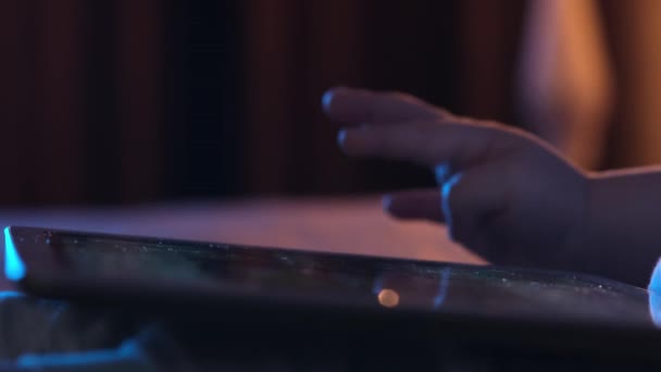 Close-up van een kleine jongen die een tablet vasthoudt met touchscreen. Kinderrollen scherm met zijn vinger op zoek naar beelden of leest nieuws feed op Internet. — Stockvideo