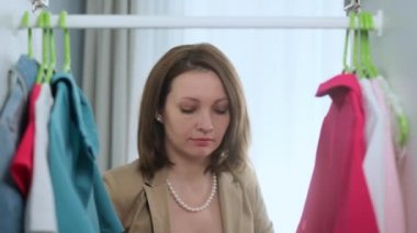 Mavi elbisesi ve boynunda inci kolyesi olan güzel bir genç kız dairesindeki dolabın kapısını açar çantasındaki ruju çıkarır ve dudaklarını boyar. Kadın partiye gidiyor..