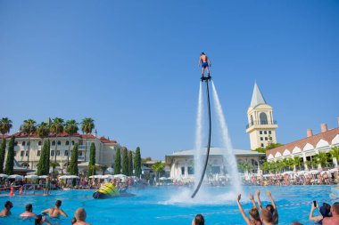 ANTALYA TURKEY 27 SEPT 2019: uçan giysili adam havuz otelinde havuz jeti veya su basıncı kuvvetiyle uçuyor. Güneşli havada kaydediliyor, genel plan.