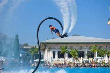 ANTALYA TURKEY 27 SEPT 2019: uçan giysili adam havuz otelinde havuz jeti veya su basıncı kuvvetiyle uçuyor. Güneşli havada kaydediliyor, genel plan.