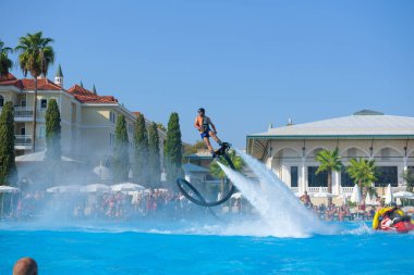 ANTALYA TURKEY 27 SEPT 2019: uçan giysili adam havuz otelinde havuz jeti veya su basıncı kuvvetiyle uçuyor. Güneşli havada kaydediliyor, genel plan.
