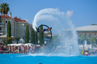 ANTALYA TURKEY 27 SEPT 2019: uçan giysili adam havuz otelinde havuz jeti veya su basıncı kuvvetiyle uçuyor. Güneşli havada kaydediliyor, genel plan.