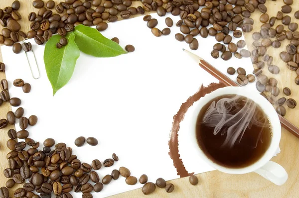 Kaffeetasse mit Bohnen und Blättern und weißem Papier und Stift — Stockfoto