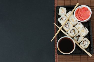 Suşi Set sashimi ve suşi rulo siyah arka plan üzerine servis. Suşi ve Sashimi rulo suşi taze yapılmış somon, karides, wasabi ve zencefil ile ayarlayın. Geleneksel Japon mutfağı. 