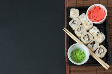 Suşi Set sashimi ve suşi rulo siyah arka plan üzerine servis. Suşi ve Sashimi rulo suşi taze yapılmış somon, karides, wasabi ve zencefil ile ayarlayın. Geleneksel Japon mutfağı. 