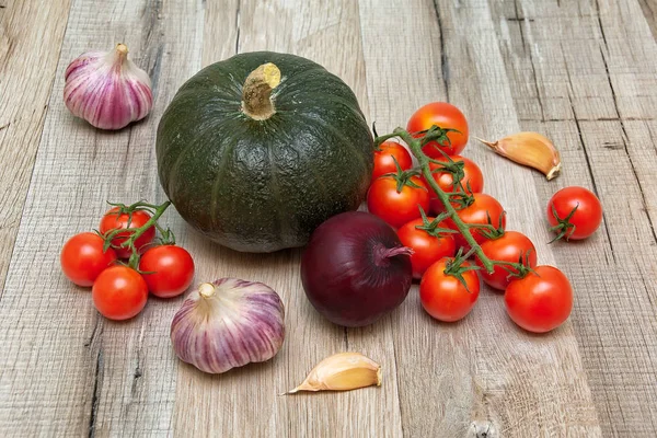Pompoenen, tomaten, ui en knoflook op een houten achtergrond — Stockfoto