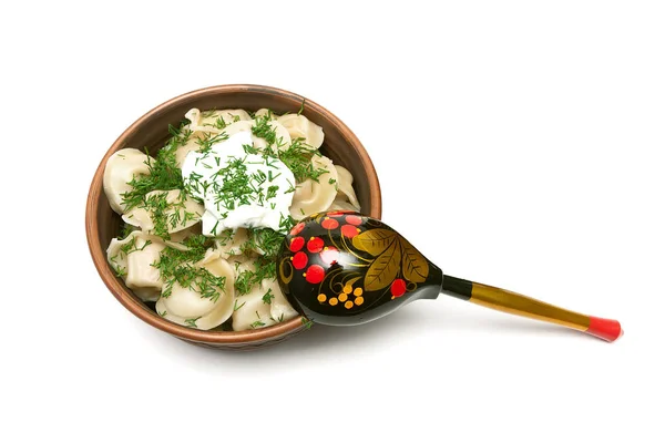 Dumplings with fresh herbs and sour cream in a clay plate on whi — Stock Photo, Image