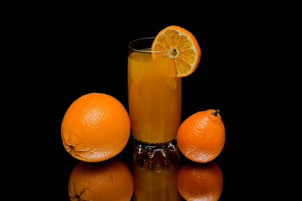 Помаранчевий, мандарин і склянка з соком на чорному тлі . — стокове фото