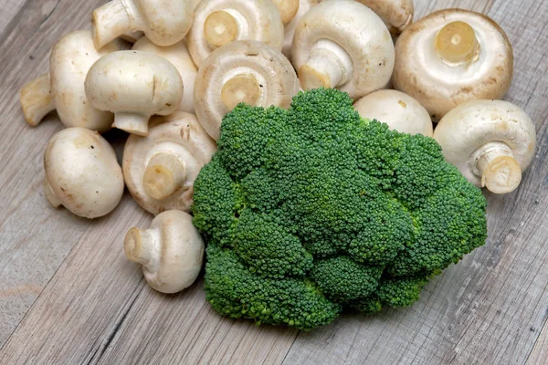 Brokkoli und Pilze auf einem Holztisch. — Stockfoto