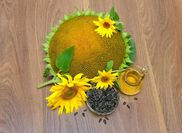 Насіння соняшнику, квіти та олія на дерев'яному фоні . — стокове фото