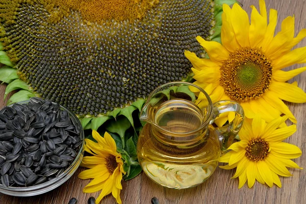 Oil, seeds and sunflowers on a wooden background. — Stock Photo, Image