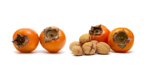 Persimmons and walnuts on a white background — Stock Photo, Image