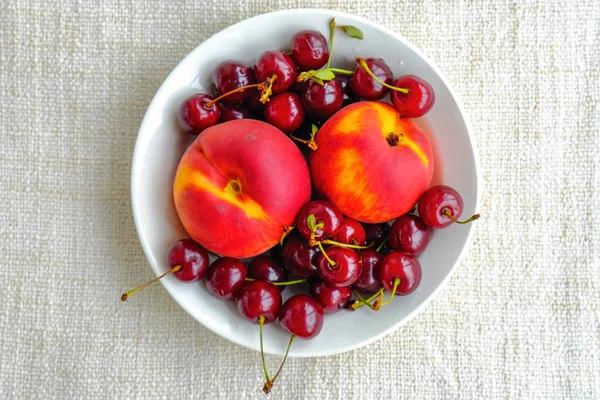 Вишни и персики на тарелке — стоковое фото