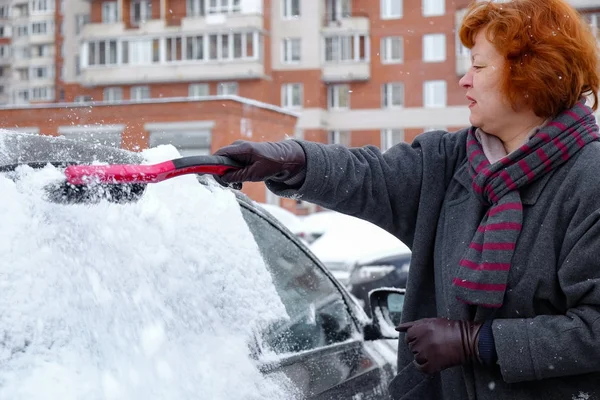 Женщина убирает снег с машины — стоковое фото