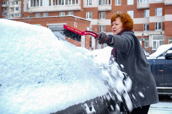 A woman cleans snow from the car — Stock Photo, Image