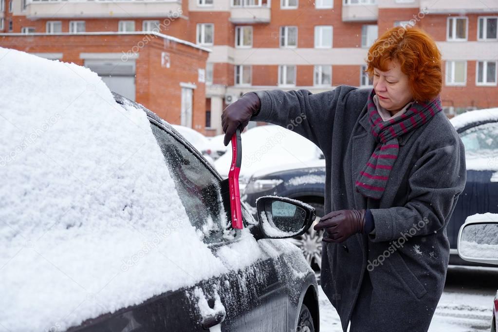 a woman cleans snow from the car