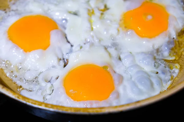 Os ovos são fritos em uma panela de ato de fritar — Fotografia de Stock