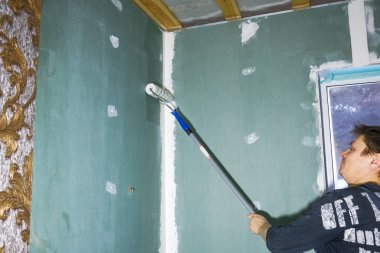 bir adam duvar kağıtları tutkallar