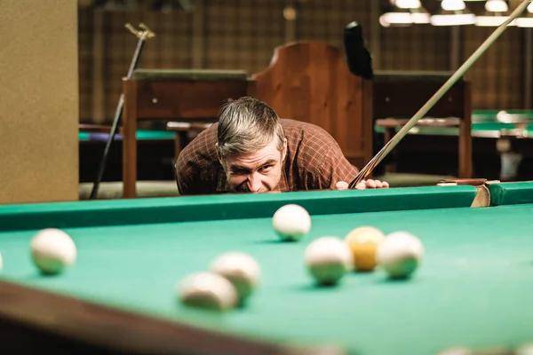 a pool player takes aim at the ball