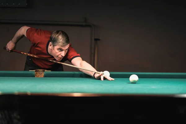 a pool player takes aim at the ball