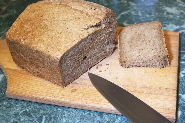 Pão assado na hora em uma tábua de corte de madeira — Fotografia de Stock