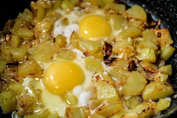 Los huevos frescos y las patatas se fríen en una sartén — Foto de Stock
