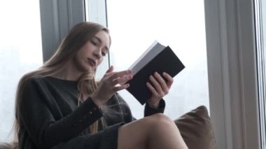 Cam kenarında bir kitap okuma genç güzel kız