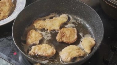 Golden chicken legs in batter fried in a pan