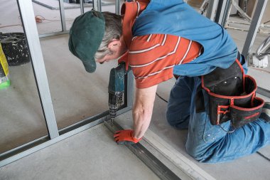 Bir işçi alçıpandan duvar yapar.