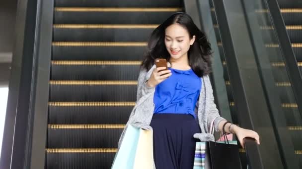 Ασιατικό κορίτσι πρόσωπο φινίρισμα ψώνια έρχεται κάτω από την κυλιόμενη σκάλα. — Αρχείο Βίντεο