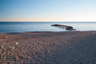 Gün batımında boş sahilde ahşap iskele