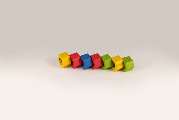 Écrous jouets en bois colorés disposés en ligne et isolés sur fond dégradé gris, plan studio — Photo