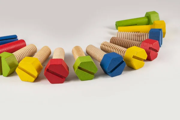 Parafusos de brinquedo de madeira coloridos dispostos, estúdio isolado filmado em fundo gradiente cinza — Fotografia de Stock