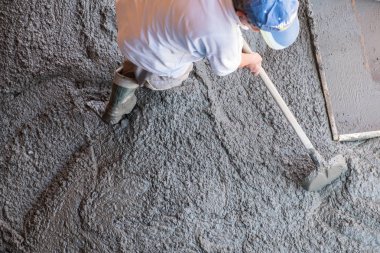 İnşaat işçisi taze dökülmüş beton yaymak