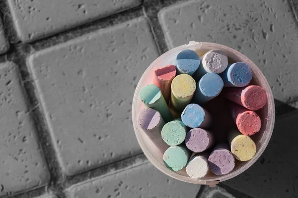 Куча цветных мелок в пластиковом ведре на тротуаре — стоковое фото