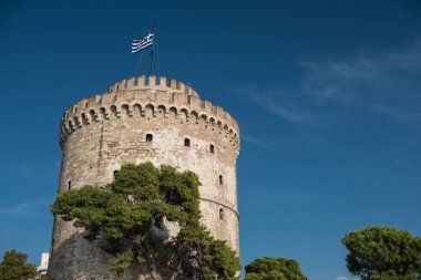 Üstünde belgili tanımlık tepe Yunan bayrağı ile antik taş kule
