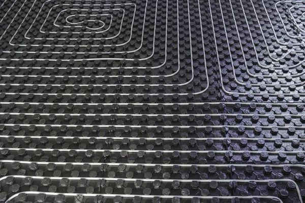 Radiant underfloor heating installation with flexible tubing mounted on insulation boards