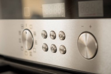 Mutfak fırını düğmeleri ve düğmeleri olan paslanmaz çelik panel.