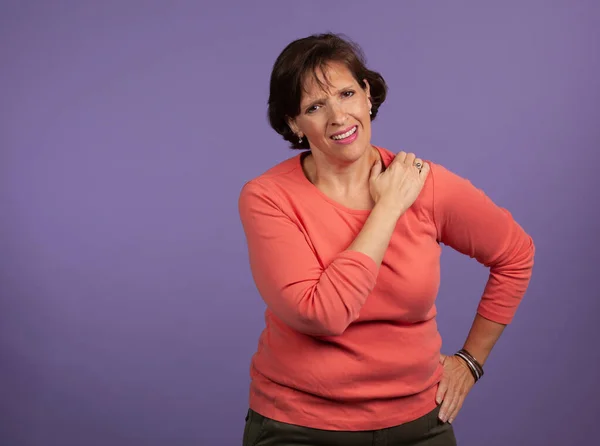 Middle Aged woman with shoulder pain holding her left shoulder a — Stock Photo, Image