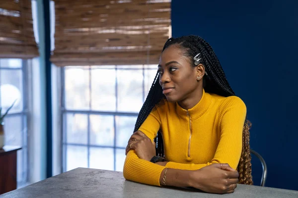 Young African American woman with yellow shirt sitting at the ki — Stock Photo, Image