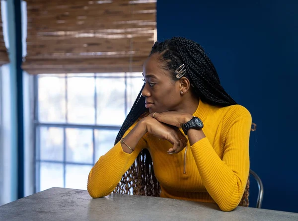Young African American woman with yellow shirt sitting at the ki — Stock Photo, Image