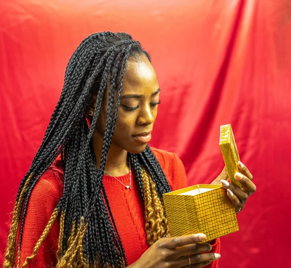 Femme vêtue de rouge regardant dans une boîte en or . — Photo