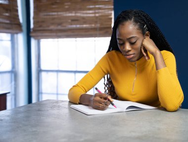 Sarı tişörtlü genç Afrikalı Amerikalı kadın Ki 'de oturuyor.