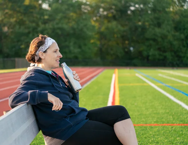 Feliz mujer activa de mediana edad sentada junto a una pista . —  Fotos de Stock