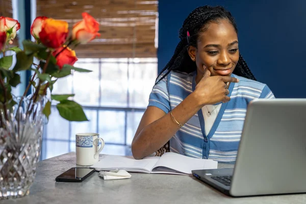 Jeune femme afro-américaine travaillant de la maison sur son ordinateur portable à — Photo