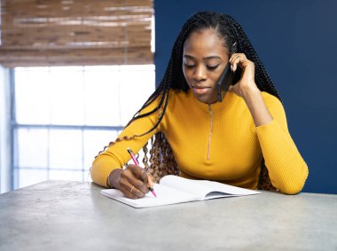 Sarı tişörtlü genç Afrikalı Amerikalı kadın Ki 'de oturuyor.