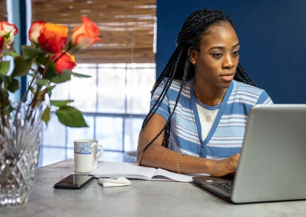 Jeune femme afro-américaine travaillant de la maison sur son ordinateur portable à — Photo