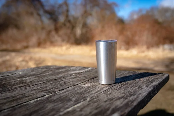 Coffee mug left behind on a picnic table — 스톡 사진