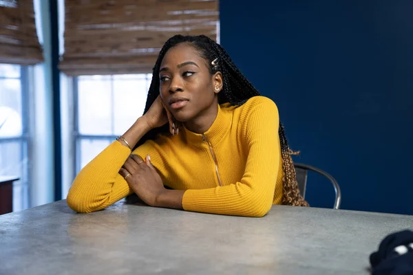 Young African American woman with yellow shirt sitting at the ki — Stock Photo, Image